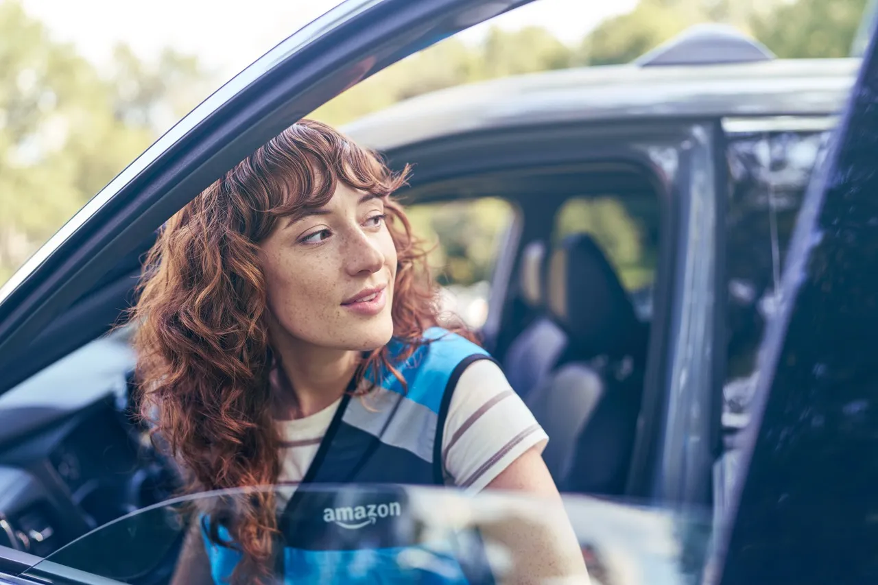 A young woman steps out of a vehicle through driver's side door.