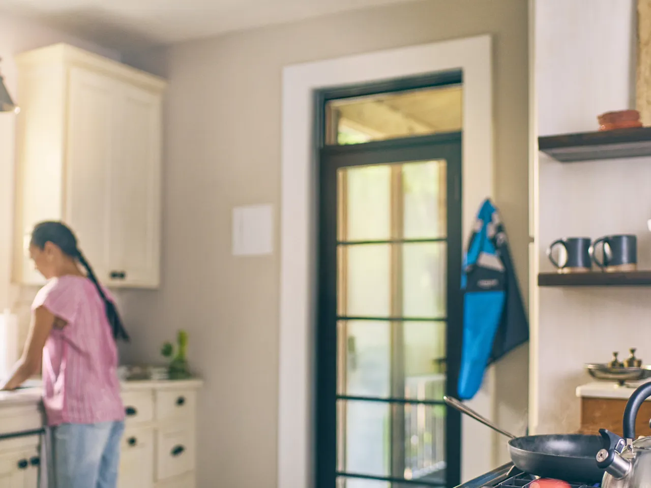 A man stands in a kitchen and looks at his phone with a smile.